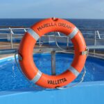 Ein Rettungsring hängt an Bord eines Kreuzfahrtschiffes vor einem Pool.